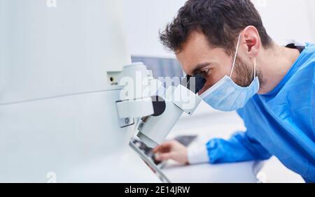 Researcher works concentrated on microscope in laboratory during Covid-19 pandemic Stock Photo