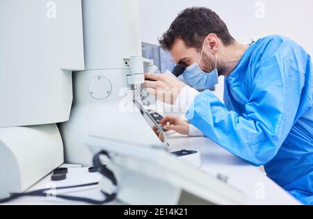 Researcher works on microscope in laboratory in Covid-19 pandemic looking for a vaccine Stock Photo