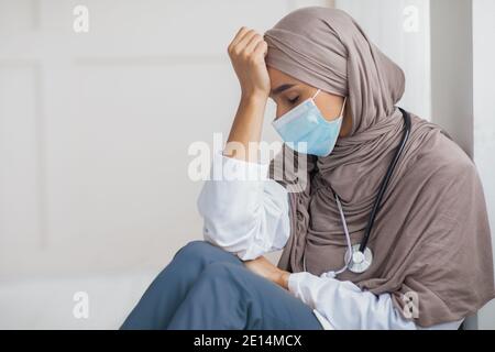 Arab woman doctor feeling exhausted, working during pandemic Stock Photo