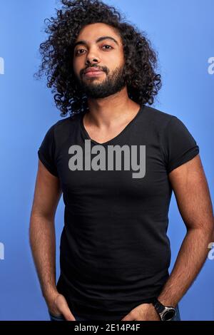 young guy posing confidently looking at camera, young bearded male with dark skin in studio Stock Photo