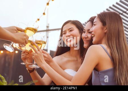 asian woman teenagers cheering and toast with white sparkling wine glass to celebrating at dinner party in summertime. celebration, relationship and f Stock Photo