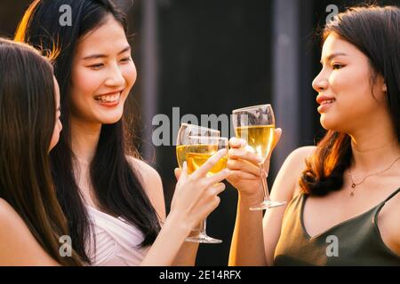 happy asian woman teenagers cheering and toast with white sparkling wine glass to celebrating at dinner party in summertime. celebration, relationship Stock Photo