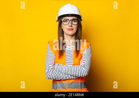 Young woman in a vest and hard hat on a yellow background. Construction concept, new building. Banner. Stock Photo
