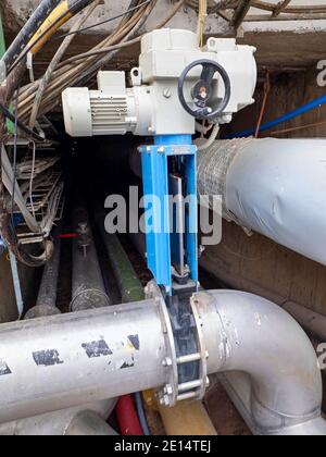 Knife gate valve remotely controlled by servo drive engine in stainless steel sludge pipe. Thick walled flanges. Stock Photo