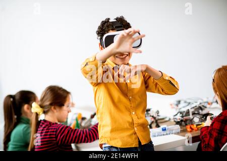 Cute little boy wearing VR virtual reality glasses in a robotics classroom Stock Photo