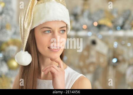 Beautiful girl in santa claus hat near Christmas tree Stock Photo