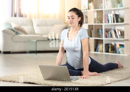 Woman doing yoga exercises watching video tutorial on laptop on the floor at home Stock Photo