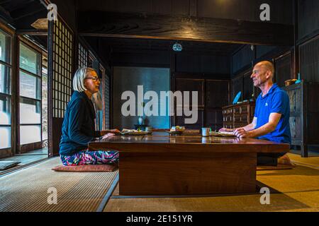 Photographer Georg Berg is sitting with Angela Berg at a low table during a kaiseki dinner in the traditional farmhouse of the Rakan kaiseki restaurant, run by chef Atsuko Kato, on the Izu Peninsula, Japan. Stock Photo