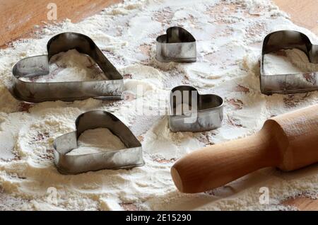 Cookie cutter molds on wooden background sprinkled with flour. Christmas, New Year, holidays preparation and creativity concept. Stock Photo