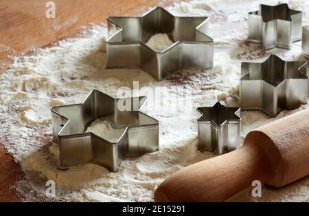Cookie cutter molds on wooden background sprinkled with flour. Christmas, New Year, holidays preparation and creativity concept. Stock Photo