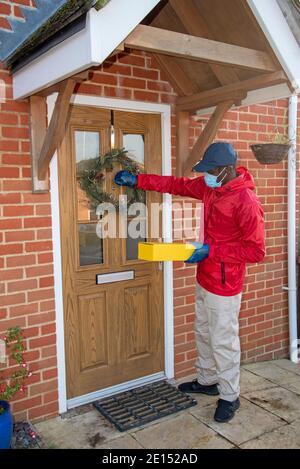 Hampshire, England, UK. 2020, Male courier delivering parcels and packages during Covid-19 epidemic wearing gloves and a mask. Stock Photo