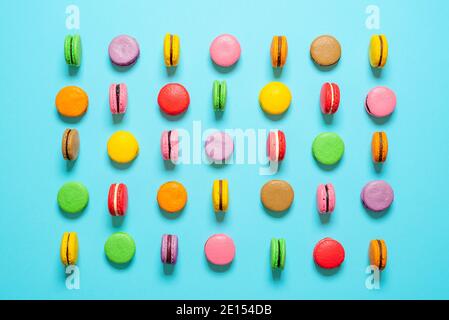 Flat lay with multi-colored homemade macarons isolated on a blue background. Top view with various colors of macarons. Stock Photo