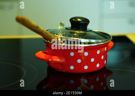 Red Enamel Bowl With White Dots On A Hob Stock Photo
