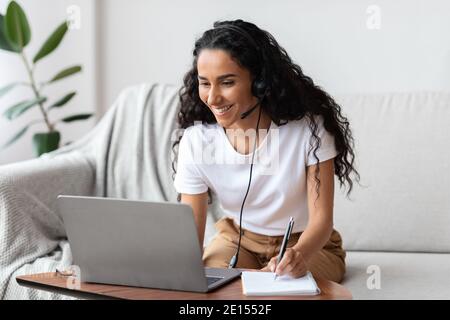Joyful young woman studying online, using laptop at home Stock Photo
