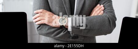 partial view of trader in formal wear and wristwatch standing with crossed arms, banner Stock Photo