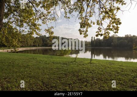 Evening beautiful landscape in the city park. Lake in the rays of the setting sun in the Botanical Garden. Stock Photo