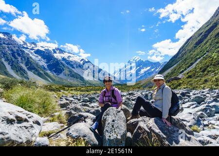 Mount Cook New Zealand - Febuary 16 2015; Hooker Valley track with tourists taking a break sitting on rocks on a  great walk of between mountain slope Stock Photo