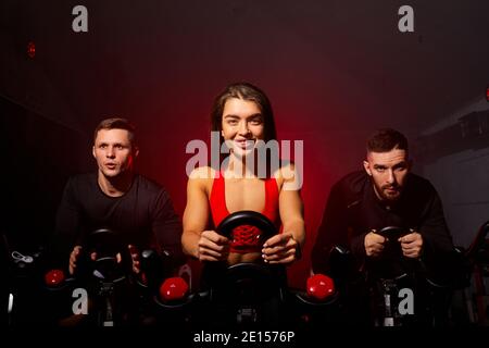 fitness workout people training on smart stationary bike indoors in gym in fitness club, athlete male and female engaged in sport Stock Photo