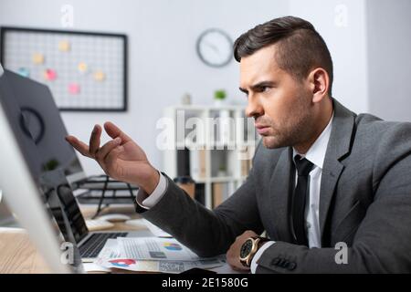 serious businessman pointing with finger at monitor on blurred foreground Stock Photo