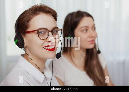 Cheerful female customer service agent wearing headset with microphone, smiling to the camera. CHarming women working at call center Stock Photo