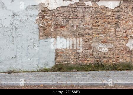 Urban street background. Old grunge obsolete brick wall and pavement Stock Photo