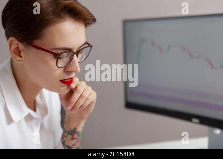 Close up of a beautiful female programmer working at her office. Attractive young businesswoman thinking, sitting in front of computer Stock Photo