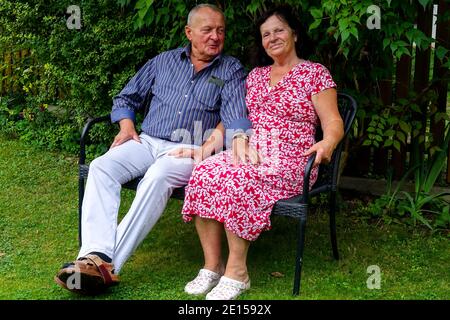 Senior couple bench, old man and woman sitting on a garden bench, old people on a bench, garden seating Stock Photo