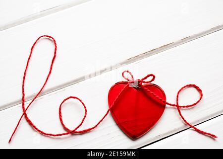 Valentine's day concept. Red heart and word love made from woolen rope on wooden background with copy space. Stock Photo