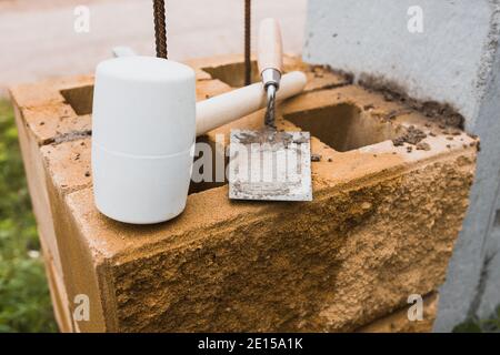 Mallet and trowel bricklayer at a construction site - laying bricks and tiles during construction and repair Stock Photo