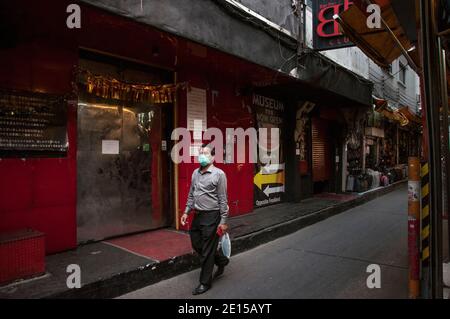 A man wearing a mask as a preventive measure against the spread of covid-19 walks past a closed nightclub at Patpong street.Thailand government ordered the closure of bars and other entertainment facilities and several other crowded venues in Bangkok starting on 1 January 2020 until 28 January 2020 amid a new wave of coronavirus outbreak in Thailand. Stock Photo