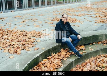 portrait picture of a young man sitting outdoors in autumn Stock Photo