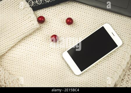 Flat lay design, winter or autumn warm and cozy composition with background knitted sweaters, decoration and smartphone photo Stock Photo