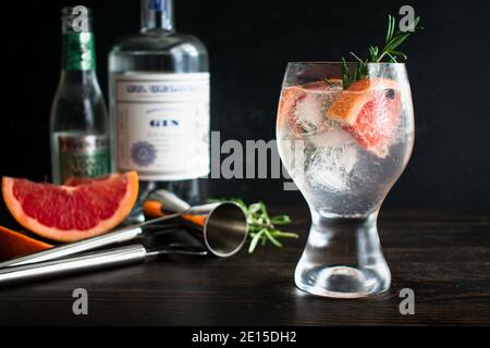 Elderflower Spanish Gin & Tonic: A gin and tonic cocktail garnished with pink grapefruit, juniper berries, and a rosemary sprig Stock Photo