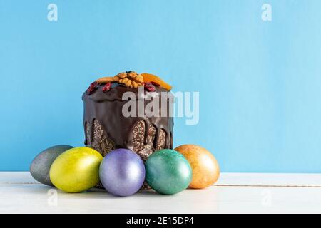 Easter cake and colored eggs on blue background. Holiday food and easter concept. Stock Photo