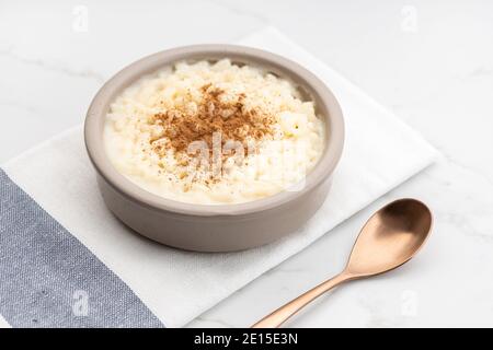 Creamy rice pudding with cinnamon in bowl on white marble table. Typical Spanish dessert Stock Photo