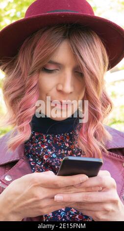 Close up portrait of a woman with a hat using a mobile phone. Stock Photo