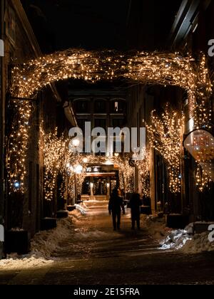 Rue Saint Amable in Montreal during winter night with viewed from Place Jacques-Cartier with one walking unrecognizable couple Stock Photo