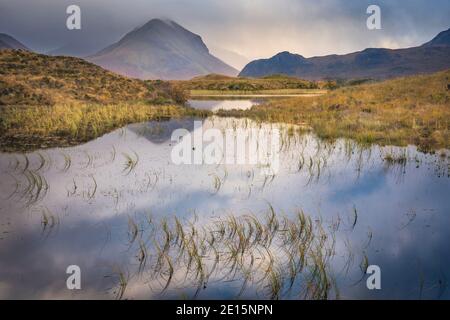 Isle of Skye, Scotland: Morning clouds clearing over the Cuillin mountains with reflections in a pond near Sligachan Stock Photo
