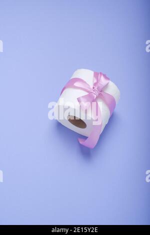 Set of toilet paper wrapped in a gift bow.The concept of a valuable actual gift. on a purple background Stock Photo