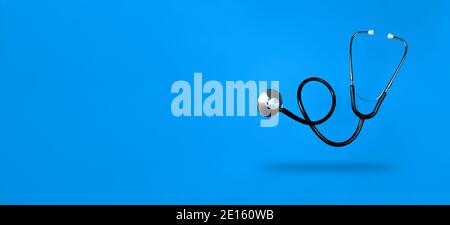 Levitating stethoscope on blue background and shadow under it with copy space. Stock photo. Stock Photo