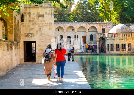 Sanli Urfa, Turkey: September 12 2020: Rear view of two female tourists near Pool of Abraham (Balikli Gol) and historic buildings in background Stock Photo