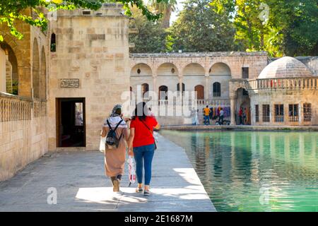 Rear view of two female tourists near Balikli Gol and historic buildings in background, Sanliurfa, Turkey Stock Photo