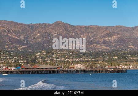 USA, California, Santa Barbara - December 18, 2020: Pier with restaurant buildings in front of Riveira upscale neighborhood on slopes of mountain rang Stock Photo