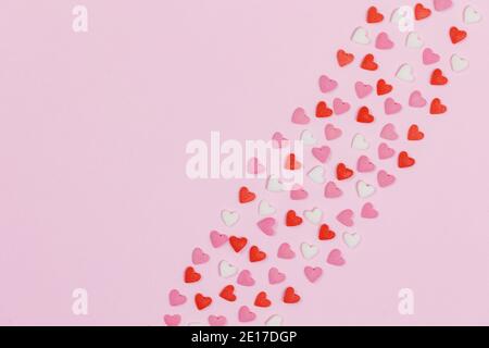 Heart shaped candies scattered on pink background love wedding concept. Valentines day pattern background. Flat lay top view. Copy space