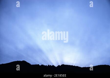 sunrays illuminate wildfire smoke over a rugged sierra mountain ridge Stock Photo