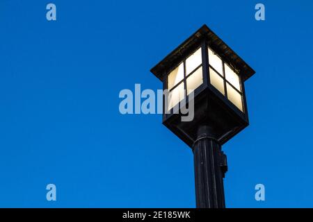 Old fashioned lamp post illuminated against the night sky with copy space. Stock Photo