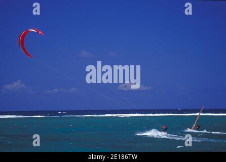 Kite surfer and sail boarder racing in clear lagoon waters off Anini Beach, east side of Kauai Stock Photo