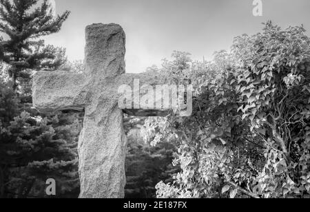 Cross In Graveyard. Black and white stone cross in a cemetery. Stock Photo