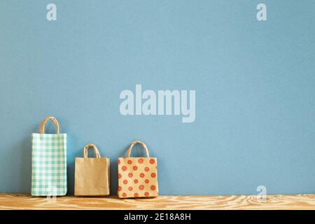 Colorful paper shopping bags on wooden table. blue background Stock Photo