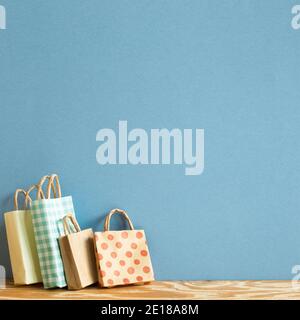 Colorful paper shopping bags on wooden table. blue background Stock Photo
